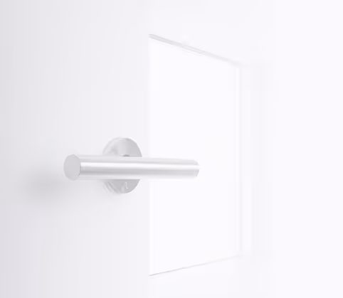 Modern silver cylindrical door handle on a white door in a bright minimalistic room.